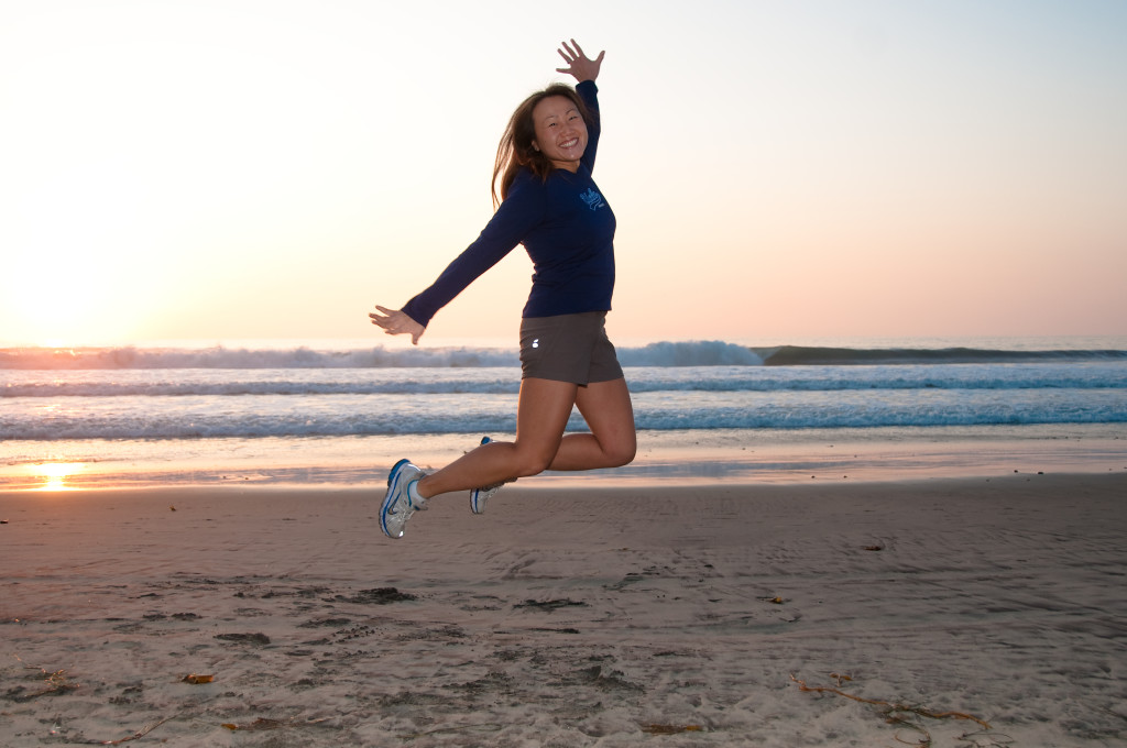 Christine lightheartedly jumping in the air at the beach.