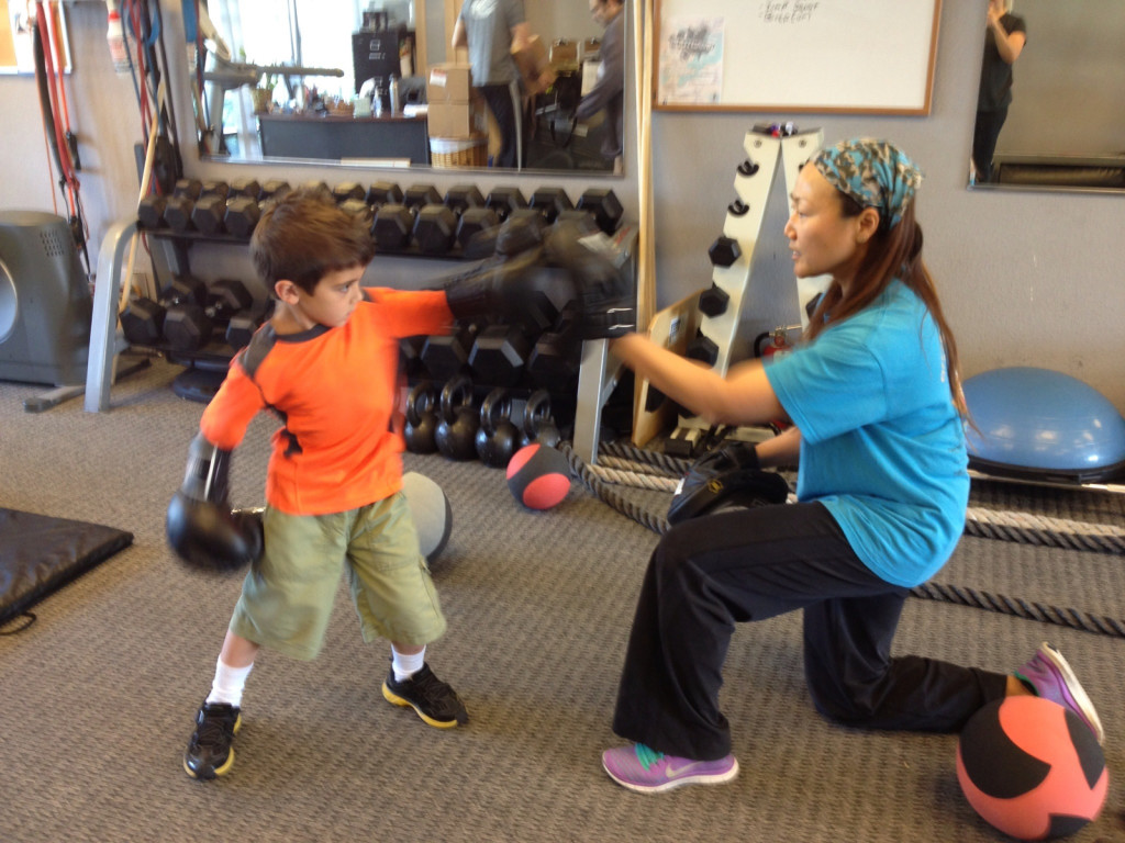 Young boy boxing with Christine.